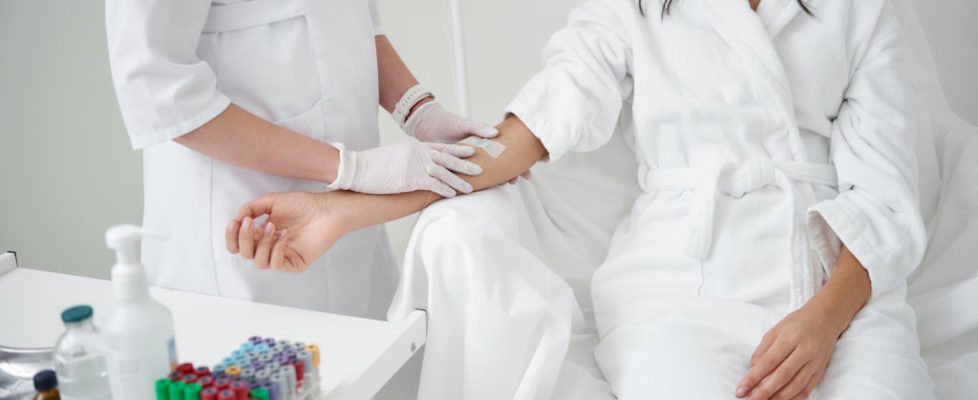 Young woman sitting in armchair and receiving intravenous treatment